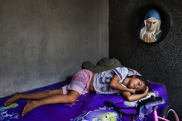 Rachael Canaveras, 10, lies on the tomb that her family's shack is built over in Manila North Cemetery.  Manila North Cemetery is home to thousands of 'informal settlers' who have built shacks using i...