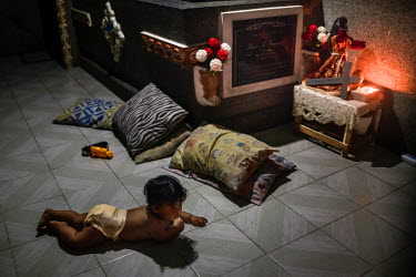A child crawls next to a tomb inside the mausoleum its family lives in at Manila North Cemetery.  Manila North Cemetery is home to thousands of 'informal settlers' who have built shacks using in and a...