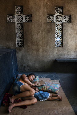 Noemi Canilang, 41, rests beside a tomb with her grandson John Lewis de la Cruz, eight months, in the Espiritu family mausoleum, in Manila North Cemetery, which she is paid to look after by the family...