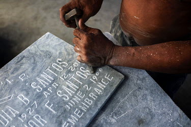 A man chisels words and numbers into a headstone in Manila North Cemetery.  Manila North Cemetery is home to thousands of 'informal settlers' who have built shacks using in and around the mausoleums,...