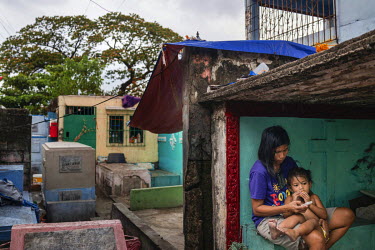 A woman sits with a child in a shack built over a tomb in Manila North Cemetery.  Manila North Cemetery is home to thousands of 'informal settlers' who have built shacks using in and around the mausol...