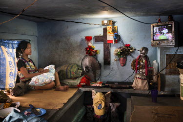 Lorgen Lozano, 14, watches soap operas on TV in the home her family built on tombs in Manila North Cemetery.  Manila North Cemetery is home to thousands of 'informal settlers' who have built shacks us...