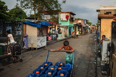 A boy pushes a cart loaded with water containers he has just filled from a communal well at Manila North Cemetery.  Manila North Cemetery is home to thousands of 'informal settlers' who have built sha...