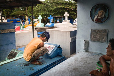 A man chisels words and numbers on a headstone at Manila North Cemetery.  Manila North Cemetery is home to thousands of 'informal settlers' who have built shacks using in and around the mausoleums, cr...
