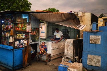 A boy sits outside a small store built over a tomb where a man plays cards at Manila North Cemetery.  Manila North Cemetery is home to thousands of 'informal settlers' who have built shacks using in a...