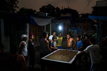 Residents playing a game based on pool using a homemade table at Manila North Cemetery.  Manila North Cemetery is home to thousands of 'informal settlers' who have built shacks using in and around the...