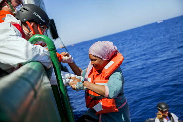 A woman is transferred from the Sea Watch rescue vessel to the larger Bourbon Argos. 67 migrants, including three babies, the smallest only four months old, were drifting in an inflatable raft on the...
