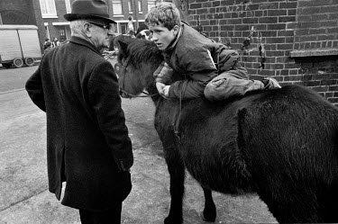 An elderly man looks on as a youth mounts a pony at the horse market in Smithfield which is held on the first Sunday of March and September.