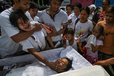 Victoria Sabado, (left) weeps as she touches the head, in a customary farewell gesture, of her son Jesus Sabado, 30, before he is interred at Manila North Cemetery. A drug user, he was killed in what...