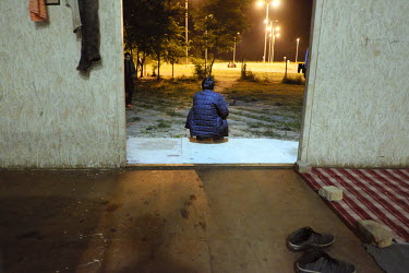 A man sits at the entrance to a tempoary shelter in Adasevci's migrant reception centre.