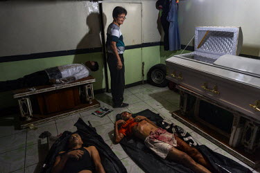 A funeral home worker in a room containing the corpses of two people killed that night in extra judicial killings and a third already embalmed in Eusebio Funeral Home.