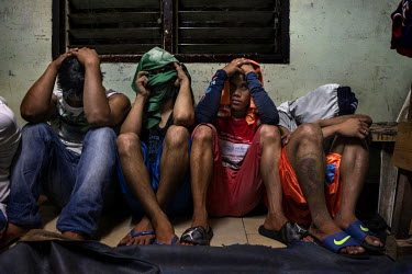 Alleged drug users cover their faces after being detained in a Police anti-drug operation.
