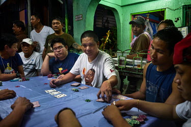 Friends and family gamble and play cards to raise money for funeral costs at the wake of Anselmo Villanueva, 22, who was gunned down by four men on motorbikes in what appeared to be a drug-related exe...