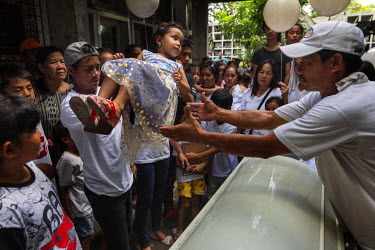 Before the coffin of Alex Hongo, 31, is interrred in Pasay Cemetery, a child is passed over it as is customary at Filipino funerals to prevent the children having nightmares. Hongo was killed on 25 No...