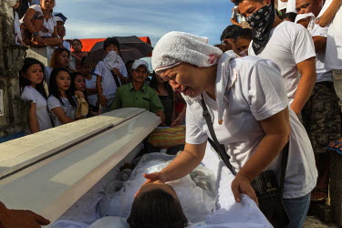Melanie Mufable leans over the cofin of her husband Christian Mufable, 34, in order to touch his face in a customary gesture of farewell before his interment at the Sangangdaan Cemetery. Mufable was k...