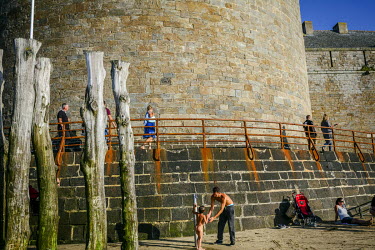 Visitors on the beach and walking the ramparts in the walled city.