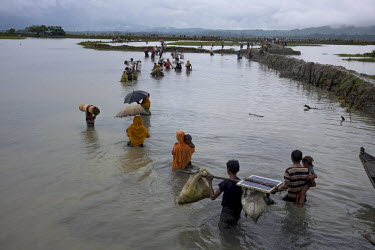 Rohingya refugees wade through waist-deep water covering flooded rice paddy fields after crossing the nearby border with Myanmar. The United Nations reported that by 11 September 2017 some 300,000 Roh...