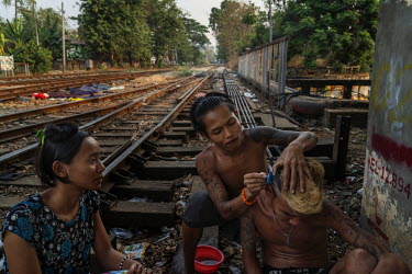 A boy shaves patterns into the hair of his friend alongside the tracks of the Yangon Circle Line train near Insein station. Each day, around 100,000 people use the route despite its antiquated rolling...