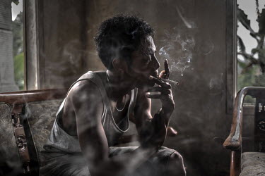 Wahyudi, 24, smokes a cigarette in his home. Since he was 18, Wahyudi has been working as a sulphur miner in the Kawah Ijen crater in order to support his family.