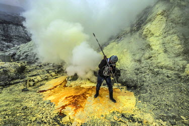 24 year old Wahyudi breaks off chunks of cooling sulphur inside the crater of the Ijen volcano. More than 200 miners come daily to collect the sulphur which occurs naturally in volcanic emissions. Aft...