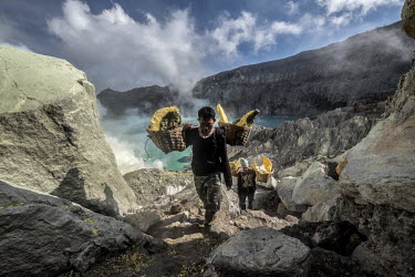 Miskadi, 36, and Mahyudi, 24, carry loads of sulphur up from inside the Ijen crater. More than 200 people come here daily to collect sulphur, which occurs naturally in volcanic emissions. After fillin...