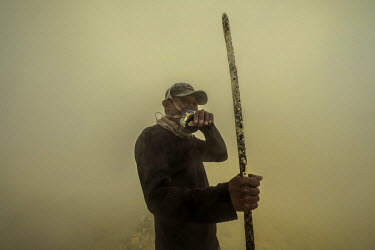 Sulphur miner Miskadi, 36, closes his eyes as a cloud of toxic sulphuric gas blows over him as he works in the Kawah Ijen crater. More than 200 people come here daily to collect sulphur, which occurs...