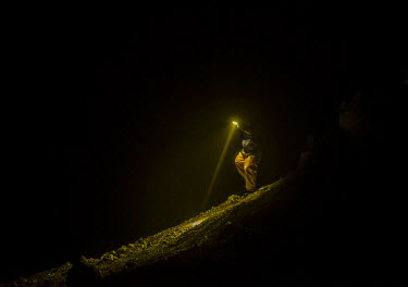 A sulphur miner navigates his way by torchlight before dawn in the Kawah Ijen crater. More than 200 people come here daily to collect sulphur, which occurs naturally in volcanic emissions. After filli...