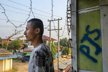 An inmate stands and looks out from the balcony of the house which serves as the Pat Jasan youth detention centre for Du Ka Htout. The graffiti, 'PJS', written on the wall next to him is the short for...