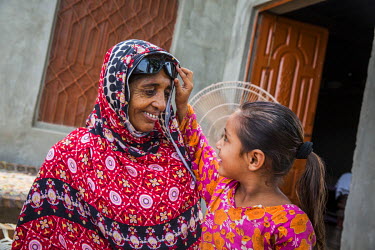 Kausar Shaheen plays with her granddaughter Iqra (7) at their home in Manhiala, Chakwal District. Kausar had an operation to remove a cataract from her right eye four days earlier and must wear sungla...