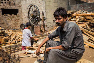 Murtaza Ghulum (30) stands by while his brother works at a wood saw at their shared home in Dhadda Kharu, near Pindi Bhaddian. Ghulum suffers from bilateral cataracts and was forced to leave his job i...
