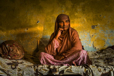 Zamurrad Bibi (55) sitting on a bed at her home. She has cataracts in both her eyes and struggles with some basic tasks in her daily life. She is waiting for a cataract operation.