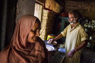 Zamurrad Bibi (55) stands in the kitchen while her husband Tariq (55) cooks a meal at their home in Awan town, Rawalpindi District. Zamurrad used to cook all the family meals but is no longer able to...