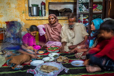Zamurrad Bibi (55) eats a meal with her extended family at their shared home in Awan town, Rawalpindi District. Zamurrad used to cook all the family meals but is no longer able to because of the catar...