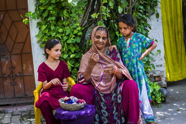 Zamurrad Bibi (55) knits as her daughter Rania (8) and niece, Ramsha (10) look on at their home in Awan town, Rawalpindi District. After having the first of two operations to remove cataracts from bot...