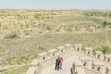A couple admire the view from one of the ramparts of the Seven Star Lakes Desert Hotel, owned by Wang Wenbiao's Elion Resources Group.  The company is heavily involved in state-sponsored afforestion a...