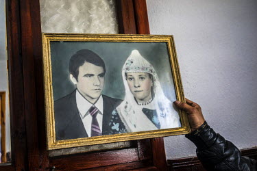 Tahrir Serdarev holds an old family wedding picture of his cousin's mother and father.