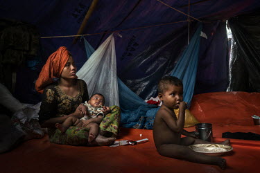 A recently arrived Rohingya woman and her children rest in a shelter built for Rohingya refugees fleeing Myanmar.