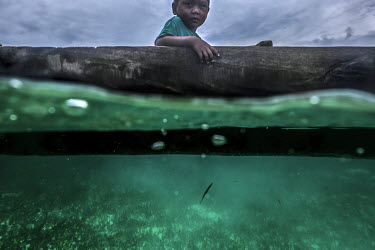 A Bajau child sits in a canoe while his father sets his nets near the island of Malenge in Indonesia.
