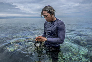 Marjono Lessing (35) rubs a sea sponge over his mask to prevent it from steaming up before a spearfishing session near the Bajau stilt-village of Kabalutan.