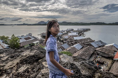 A Bajau girl stands on the top of a rock in the stilt village of Kabalutan. After centuries spent living on boats, roaming the seas of the 'Coral Triangle', most Bajau have now given up the nomadic li...