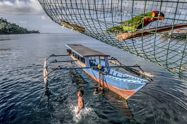A Bajau child leaps from a boat into the water.