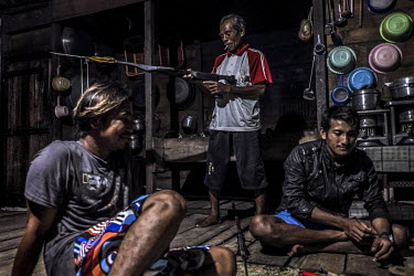 Lessing Kulo (61) examines his son's speargun at home in the evening in the Bajau village of Kabalutan.