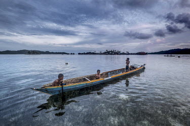 Bajau children paddle a canoe through the waters off Malenge island. Bajau learn to swim and manage boats from a very early age.
