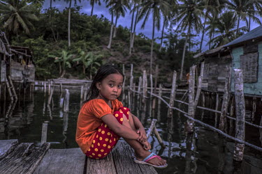 A Bajau girl sits on the end of a broken walkway in the village of Kabalutan.
