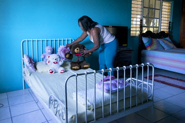 A woman laying out teddy bears on a bed in her spare room in a house in the Beverly Hills neighbourhood of Kingston. Her children all live abroad, and her grandchildren are yet to visit her in Jamaica...