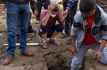 Fadhil Suleiman (35) holds his head in his hands as the body of his mother is dug up from her temporary grave in western Mosul. The 61 year old was exhumed in order to formally identifiy her through h...