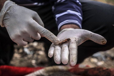 Forensics officer, Qais Abdullah, displays a piece of shrapnel removed from the corpse of Aliya Saeed, who was killed by a mortar shell in June 2017. Abdullah is part of a three man team tasked with i...