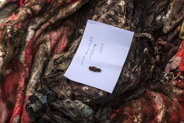 A note written by members of a forensics team lies atop the recently exhumed body of Aliya Saeed, who was killed by a mortar strike in June 2017.