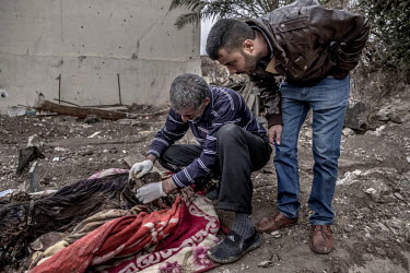 Qais Abdullah and Sdiyaldin Shamsaldin, members of a forensics team, examine the body of Aliya Saeed, who was killed in June 2017 by a mortar strike in western Mosul. They are part of a three man team...