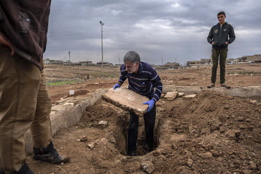 Qais Abdullah removes a slab of concrete from the grave of three year old Qasar during the exhumation of his body. Qasar was killed by shrapnel whilst fleeing ISIS held territory in Mosul.